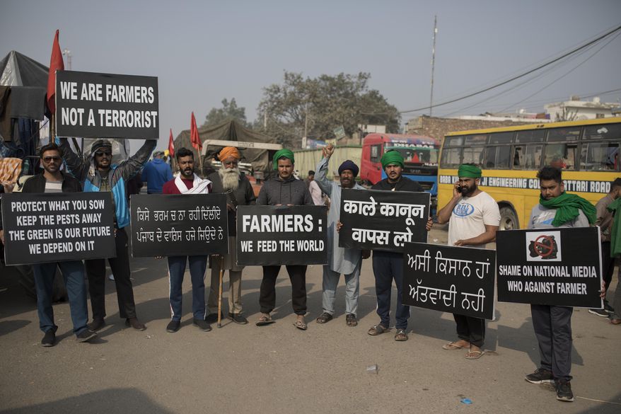 Protesting farmers hold placards at the border between Delhi and Haryana state, Tuesday, Dec. 1, 2020. Talks between protesting farmers and the Indian government failed Tuesday after both the parties could not reach a common ground to discuss the new farming laws, protests against which have intensified after entering their sixth day. More growers joined giant demonstrations and choked roads to India's Capital by hunkering down along with their trucks and tractors. (AP Photo/Altaf Qadri)