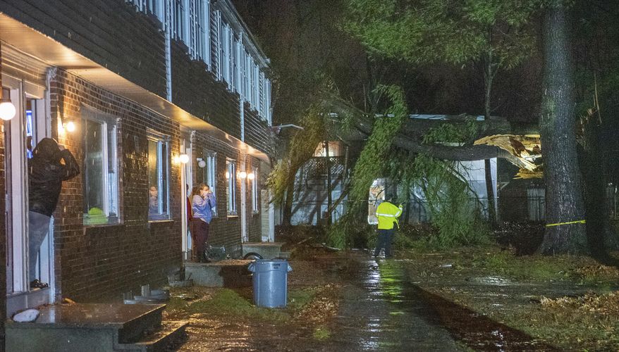 A person looks at a large tree that crashed into the side of an apartment building on Tall Pines Drive in River Valley Village in Lewiston, Maine, Monday, Nov. 30, 2020, during a severe storm. (Russ Dillingham/Sun Journal via AP)