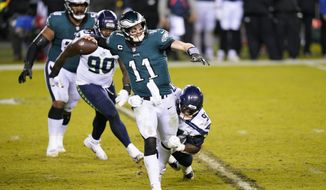 Philadelphia Eagles&#x27; Carson Wentz (11) is grabbed by Seattle Seahawks&#x27; Poona Ford (97) during the second half of an NFL football game, Monday, Nov. 30, 2020, in Philadelphia. (AP Photo/Chris Szagola)