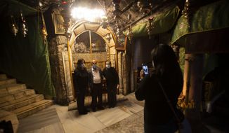 Christian take photos inside the Grotto of the Church of the Nativity, traditionally believed to be the birthplace of Jesus Christ, in the West Bank city of Bethlehem, Monday, Nov. 23, 2020. Normally packed with tourists from around the world at this time of year, Bethlehem resembles a ghost town — with hotels, restaurants and souvenir shops shuttered by the pandemic. (AP Photo/Majdi Mohammed)