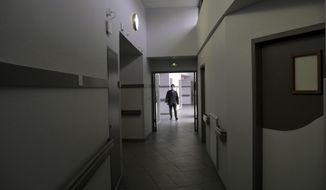 A patient walks on a corridor of the Rouvray psychiatric hospital, in Rouen, western France, Wednesday, Nov. 25, 2020. Lockdowns that France has used to fight the coronavirus have come at considerable cost to mental health. Surveying points to a surge of depression most acute among people without work, in financial hardship and young adults. (AP Photo/Thibault Camus)