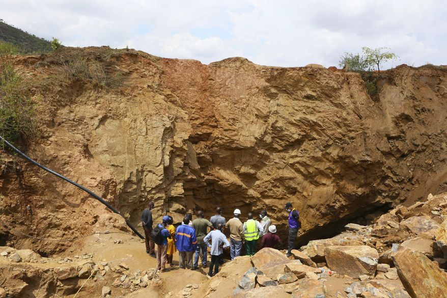 Government officials are seen at the sight of an abandoned mine where artisanal miners are trapped underground in Bindura about 70 kilometres northeast of the capital Harare, Tuesday, Dec, 1, 2020.  Artisanal miners illegally digging for gold in a disused shaft blasted a support pillar resulting in them being trapped. A government rescue agency says 10 miners are still trapped under the rabble with hopes of finding survivors diminishing after rescuers retrieved one body on Monday according to a government spokesman.(AP Photo/Tsvangirayi Mukwazhi)