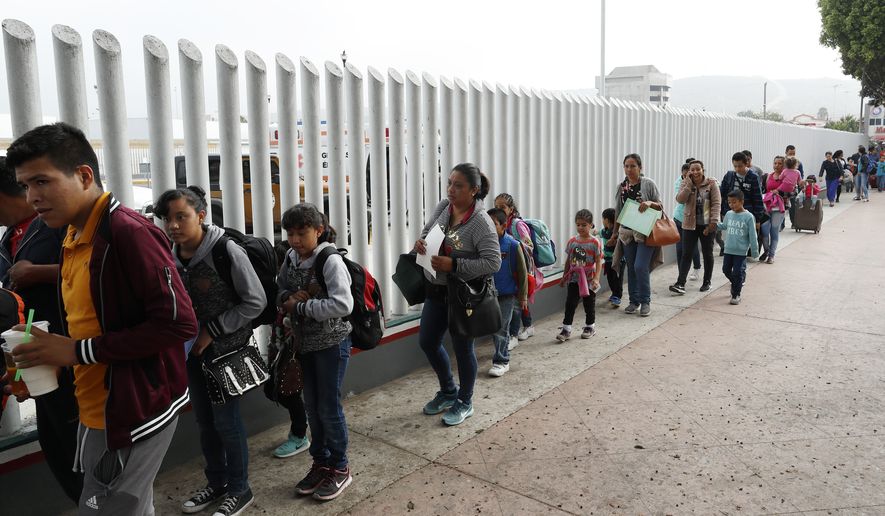 This July 26, 2018, photo shows people lining up to cross into the United States to begin the process of applying for asylum near the San Ysidro port of entry in Tijuana, Mexico. A court-appointed committee has yet to find the parents of 628 children separated at the border early in the Trump administration. (AP Photo/Gregory Bull) **FILE**