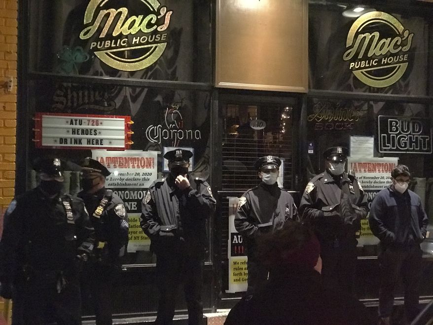 Officers from the New York City sheriff&#39;s office stand outside Mac&#39;s Public House on Tuesday, Dec. 1, 2020, on Staten Island, N.Y.  An owner of the New York City bar that was providing indoor service in defiance of coronavirus restrictions was arrested after a sting in which plainclothes officers went inside and ordered food and beverages, the city sheriff&#39;s office said. (Irene Spezzamonte/Staten Island Advance via AP)