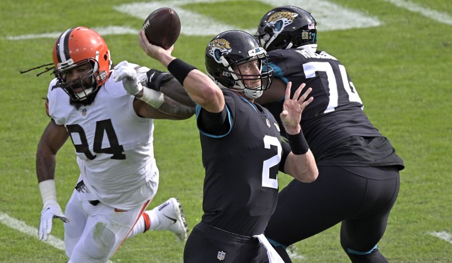 Jacksonville Jaguars quarterback Mike Glennon (2) throws a pass as he is rushed by Cleveland Browns defensive end Adrian Clayborn, left, during the first half of an NFL football game, Sunday, Nov. 29, 2020, in Jacksonville, Fla. (AP Photo/Phelan M. Ebenhack)