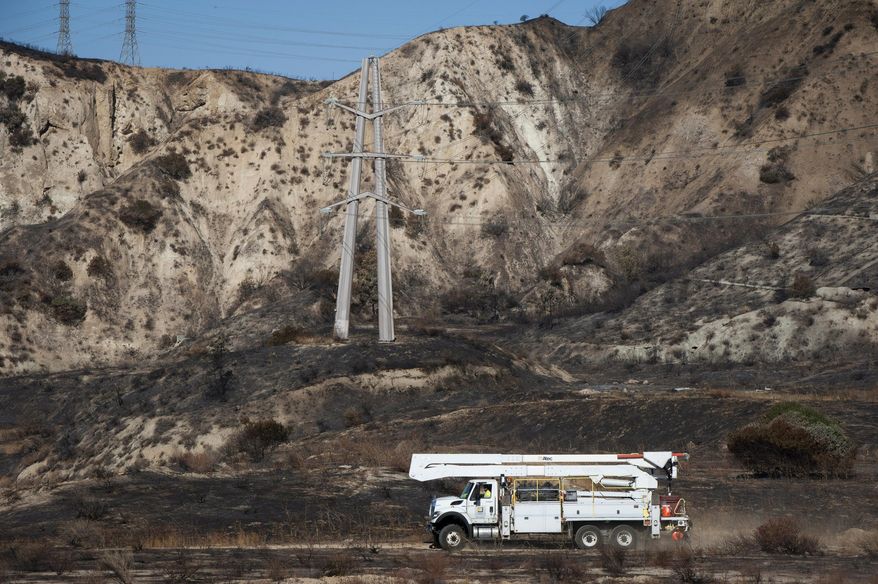FILE - In this Oct. 15, 2019, file photo, Southern California Edison trucks arrive at the site of a transformer tower in Sylmar, Calif., suspected of being responsible for starting the Saddleridge fire. Southern California utilities say they may cut power to more than 300,000 customers this week as dry, gusty weather raises the threat of wildfire danger. The winds can knock down power lines and spark blazes. Southern California Edison says it's considering cutting power to nearly 237,000 customers as a precaution, possibly beginning Wednesday evening, Dec. 2, 2020, and running into the weekend. (AP Photo/Christian Monterrosa, File)