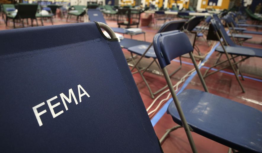 FILE - In this March 24, 2020, file photo, a portable cot, with the Federal Emergency Management Agency logo FEMA printed on the backrest, and other cots line the basketball court at a makeshift medical facility in a gymnasium at Southern New Hampshire University in Manchester, N.H. More than a quarter of workers at the FEMAsay they have harassed or discriminated against based on their gender or race, according to a survey released Dec. 2, 2020, as part of the fallout from allegations of sexual harassment by a senior official at the agency. (AP Photo/Charles Krupa, File)