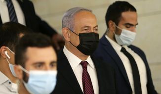 Israeli Prime Minister Benjamin Netanyahu, center, arrives at the Israeli Knesset (Parliament) ahead of a vote to dissolve the Knesset, in Jerusalem, Wednesday, Dec. 2 2020. The Israeli parliament passed a preliminary proposal to dissolve itself on Wednesday, setting up a possible fourth national election in under two years while the country is in the grip of the coronavirus pandemic.(Alex Kolomoisky/Pool via AP)