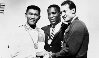 In this Sept. 7, 1960, file photo, Rafer Johnson of Kingsburg, Calif., is flanked by runners-up, Chuan-Kwang Yang, left, of Taiwan, and Vasily Kuznetsov of Russia, as they join in three-way handshake after receiving medals for the decathlon event of the Olympics in Rome, Italy. Rafer Johnson, who won the decathlon at the 1960 Rome Olympics and helped subdue Robert F. Kennedy&#39;s assassin in 1968, died Wednesday, Dec. 2, 2020. He was 86. He died at his home in the Sherman Oaks section of Los Angeles, according to family friend Michael Roth. (AP Photo) **FILE**
