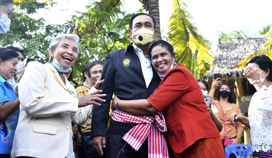In this photo released by Government Spokesman Office, a well-wisher hugs Thailand&#x27;s Prime Minister Prayuth Chan-ocha in Samut Songkhram province, Thailand, Wednesday, Dec. 2, 2020. Thailand’s highest court is set to rule Wednesday on whether Prayuth has breached ethics clauses in the country’s constitution and should be ousted from his position. (Government Spokesman Office via AP)