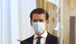 Austrian Chancellor Sebastian Kurz wears a face mask as he arrives behind plexiglass shields for a press conference at the federal chancellery in Vienna, Austria, Wednesday, Dec. 2, 2020. The Austrian government has moved to restrict freedom of movement for people, in an effort to slow the onset of the COVID-19 coronavirus. (AP Photo/Ronald Zak)