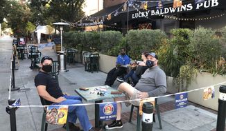 Anthony Angulo, left, and Jeff Koloski sit on the patio of Lucky Baldwin&#x27;s pub on Monday, Nov. 30, 2020 in Pasadena, Calif. It was a rare sight after restaurants in Los Angeles County were ordered to halt serving food to diners to stop the spread of coronavirus: tables and chairs were set up outdoors in Pasadena. The city in the Los Angeles suburbs has become an island in the center of the nation&#x27;s most populous county, where a surge of COVID-19 cases last week led to a three-week end to outdoor dining and California&#x27;s first stay-home order since the pandemic began to spread across the state in March. (AP Photo/Christopher Weber)