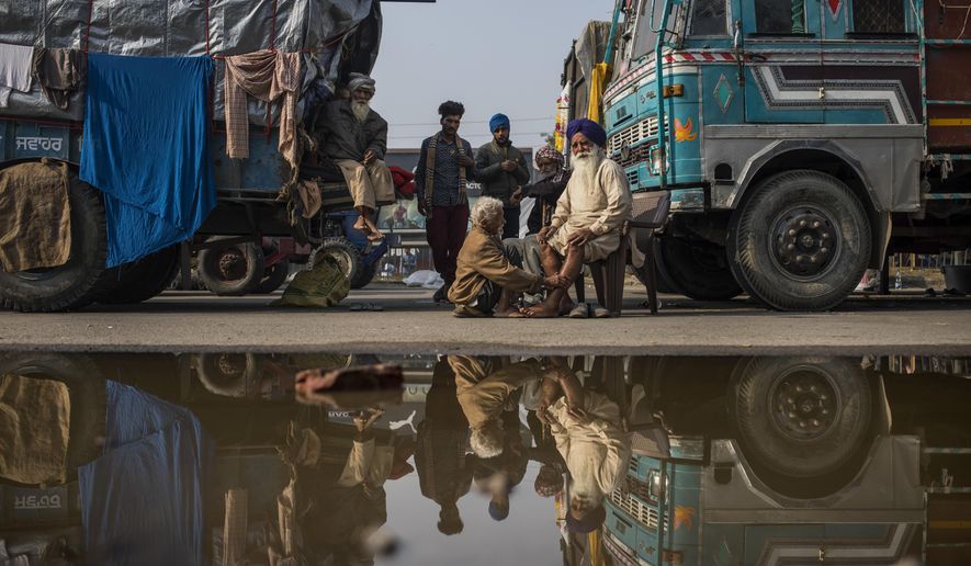 Indian farmer Surender Singh, 70, sits on a chair and gets a massage, next to a truck parked on a highway as part of protests against new farm bills, at the Delhi-Haryana state border, India, Tuesday, Dec. 1, 2020. The farmers are protesting new laws they say will result in their exploitation by corporations, eventually rendering them landless. It’s a siege of sorts and the mood among the protesting farmers is boisterous. Their rallying call is “Inquilab Zindabad” (“Long live the revolution”). (AP Photo/Altaf Qadri)