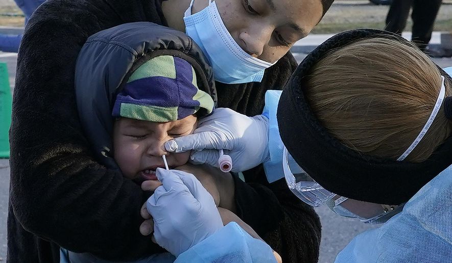 Jamillette Gomes holds her two-year-old son, Avian, as he receives a COVID-19 test, Thursday, Dec. 3, 2020, in Lawrence, Mass. (AP Photo/Elise Amendola)