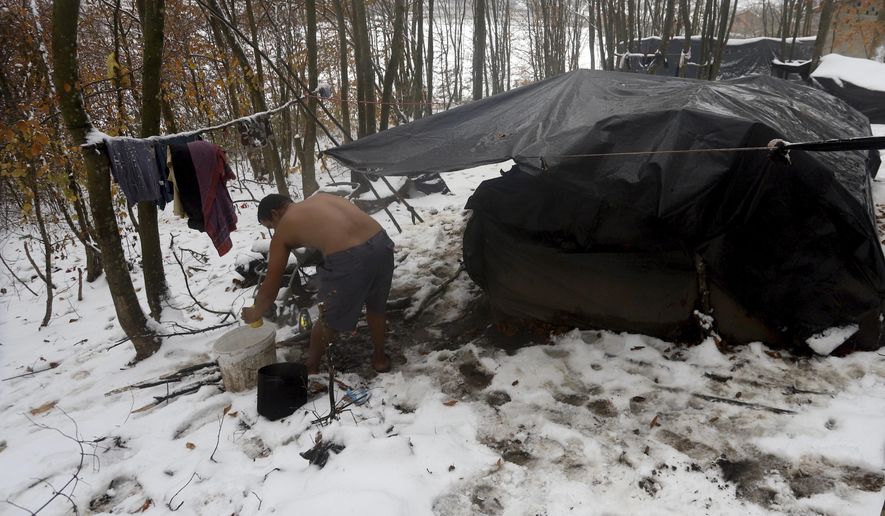 A migrant cleans himself up next to improvised tents at a makeshift camp in a forest outside Velika Kladusa, Bosnia, Thursday, Dec. 3. 2020. Their long journeys already filled with uncertainty and hardship, migrants stranded in Bosnia are now facing another adversity _ a cold Balkan winter. As this season's first snow fell this week in parts of the region, many migrants living in make-shift tent settlements in western Bosnia are struggling to stay dry and warm. (AP Photo/Joan Giralt)