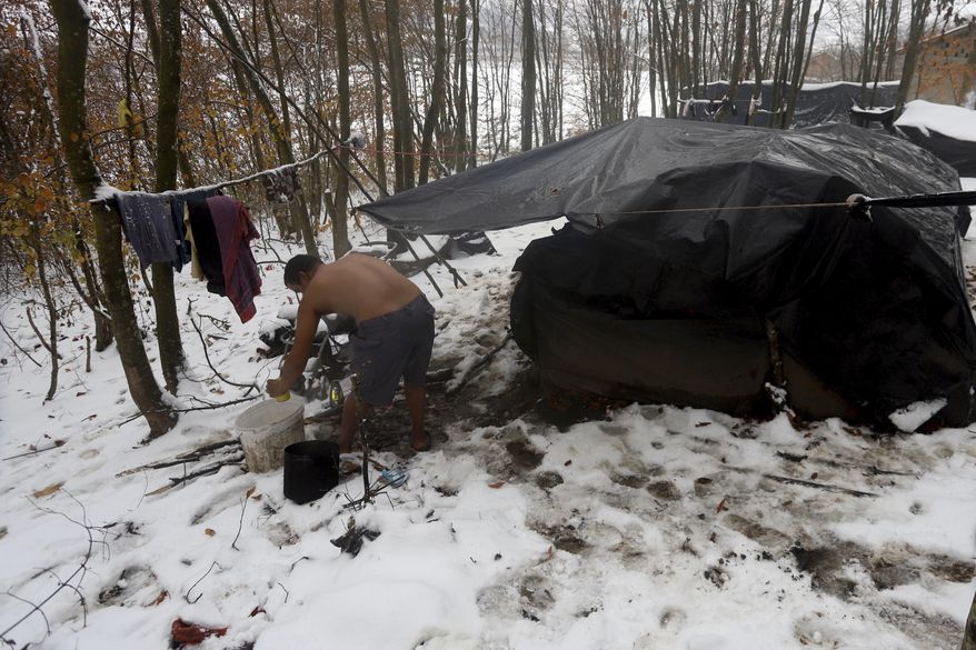 A migrant cleans himself up next to improvised tents at a makeshift camp in a forest outside Velika Kladusa, Bosnia, Thursday, Dec. 3. 2020. Their long journeys already filled with uncertainty and hardship, migrants stranded in Bosnia are now facing another adversity _ a cold Balkan winter. As this season's first snow fell this week in parts of the region, many migrants living in make-shift tent settlements in western Bosnia are struggling to stay dry and warm. (AP Photo/Joan Giralt)