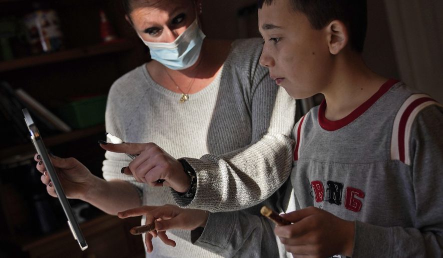 Paraprofessional Jessica Wein helps Josh Nazzaro answer questions from his teacher while attending class virtually from his home in Wharton, N.J., Wednesday, Nov. 18, 2020. The pandemic is threatening to wipe out the educational progress made by many of the nation’s 7 million students with disabilities. That's according to advocates, who say the extended months of learning from home and erratic attempts to reopen schools are deepening a crisis that began with the switch to distance learning in March. (AP Photo/Seth Wenig) **FILE**