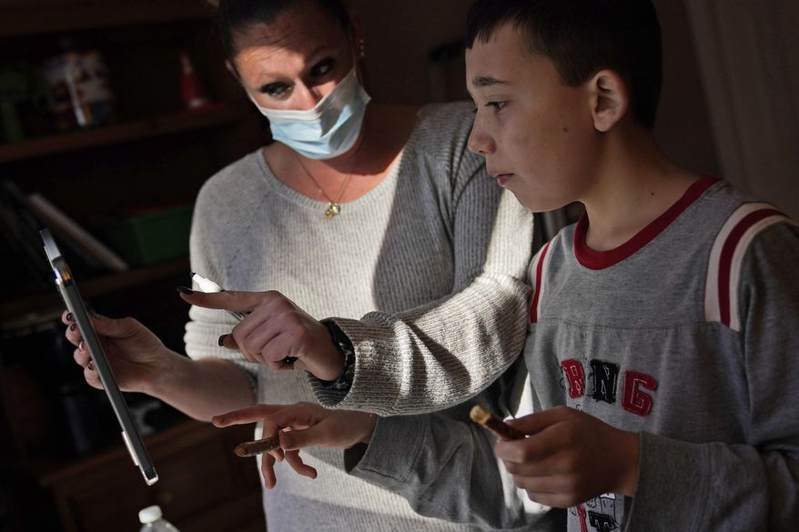 Paraprofessional Jessica Wein helps Josh Nazzaro answer questions from his teacher while attending class virtually from his home in Wharton, N.J., Wednesday, Nov. 18, 2020. The pandemic is threatening to wipe out the educational progress made by many of the nation’s 7 million students with disabilities. That's according to advocates, who say the extended months of learning from home and erratic attempts to reopen schools are deepening a crisis that began with the switch to distance learning in March. (AP Photo/Seth Wenig) **FILE**