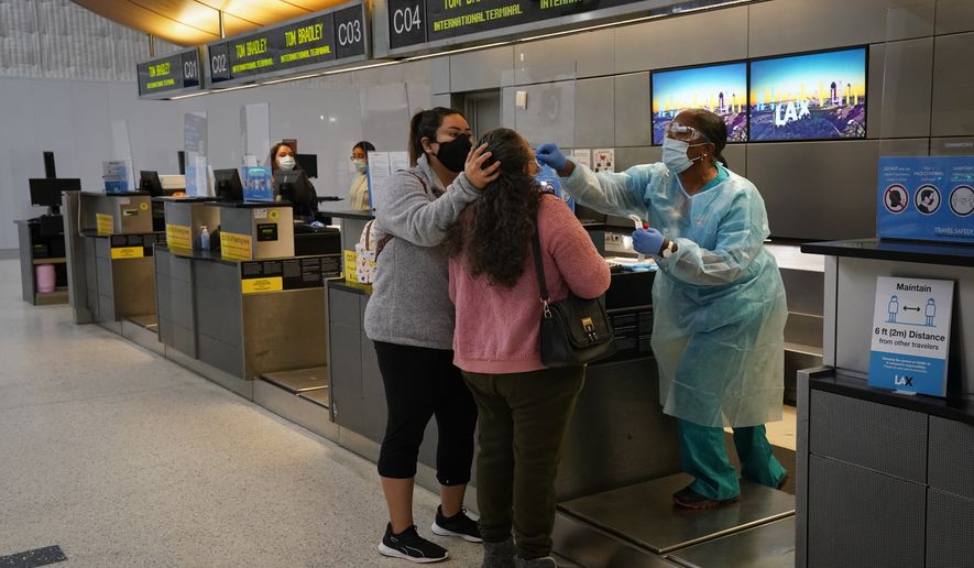 In this Nov. 23, 2020, file photo, licensed vocational nurse Caren Williams, left, collects a nasal swab sample from a traveler at a COVID-19 testing site at the Los Angeles International Airport in Los Angeles. Data from roadways and airports shows millions could not resist the urge to gather on Thanksgiving, even during a pandemic. (AP Photo/Jae C. Hong)