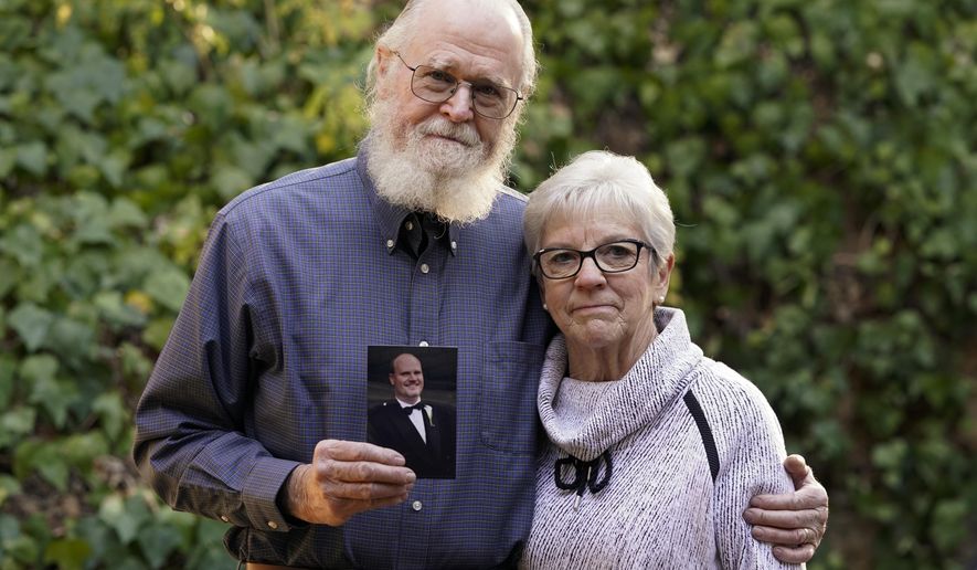 Clark McIlvain and Kathleen McIlvain hold a photo of their son, Charles McIlvain, at their home on Thursday, Dec. 3, 2020, in Woodland Hills, Calif. Charles McIlvain was one of 34 people killed when dive boat Conception caught fire and sank off the coast of California on Sept. 2, 2019. (AP Photo/Ashley Landis)