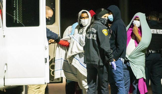 People are handcuffed together in pairs and loaded into vans as police investigate a possible human smuggling operation, Thursday night, Dec. 4, 2020, in Houston. About 30 people were taken to the gymnasium of a nearby elementary school and were eventually transported away. Investigators say the victims came from Mexico, Honduras, El Salvador and Cuba. (Mark Mulligan/Houston Chronicle via AP) ** FILE **