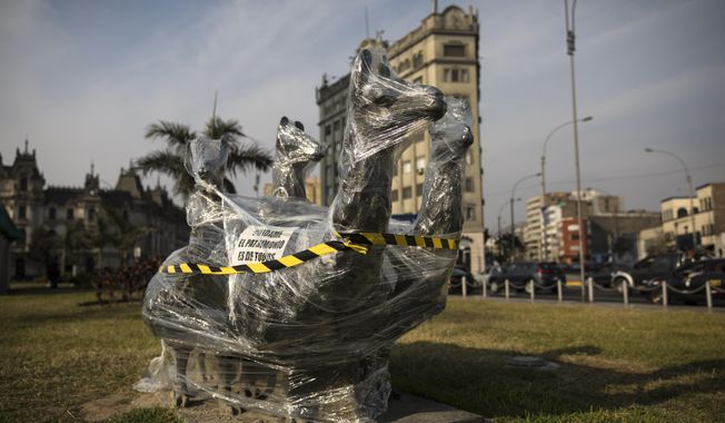 A bronze sculpture of four llamas is wrapped in plastic near the Palace of Justice in Lima, Peru, Saturday, Nov. 21, 2020. The municipality of Lima for the the first time in 485 years took precautions to protect historical monuments and statues, while Peru was mired in a whirlwind of demonstrations and a political crisis that resulted with three presidents in nine days. (AP Photo/Rodrigo Abd)