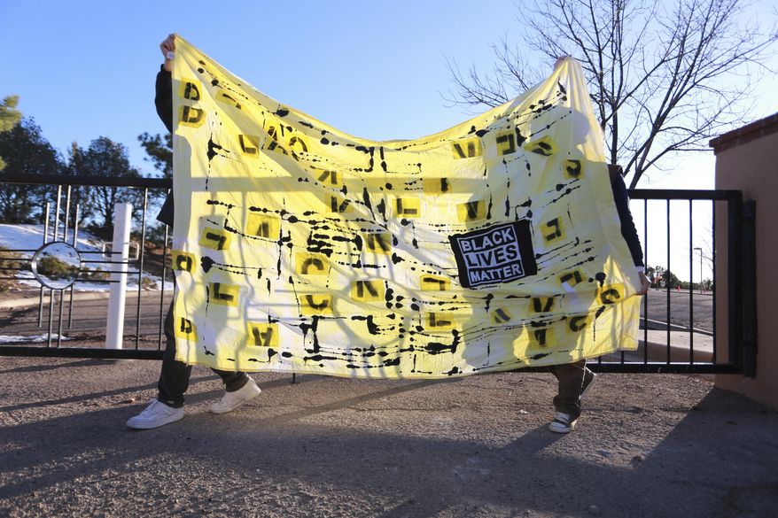 Protesters carry a banner in front of the official residence of Gov. Michelle Lujan Grisham as part of an in-person and virtual for justice in the police shooting of a Black man two weeks earlier on Friday, Dec. 4, 2020, in Santa Fe, N.M. Family of Rodney Applewhite, 25, have been asking for additional details in the incident that led to him being shot by police. New Mexico State Police released additional information after the protest, and released his name to the public. Applewhite, of South Bend, Indiana, was driving through New Mexico on the way to a family Thanksgiving in Phoenix, Arizona, when police shot him on Nov. 19, his family said. (AP Photo/Cedar Attanasio)