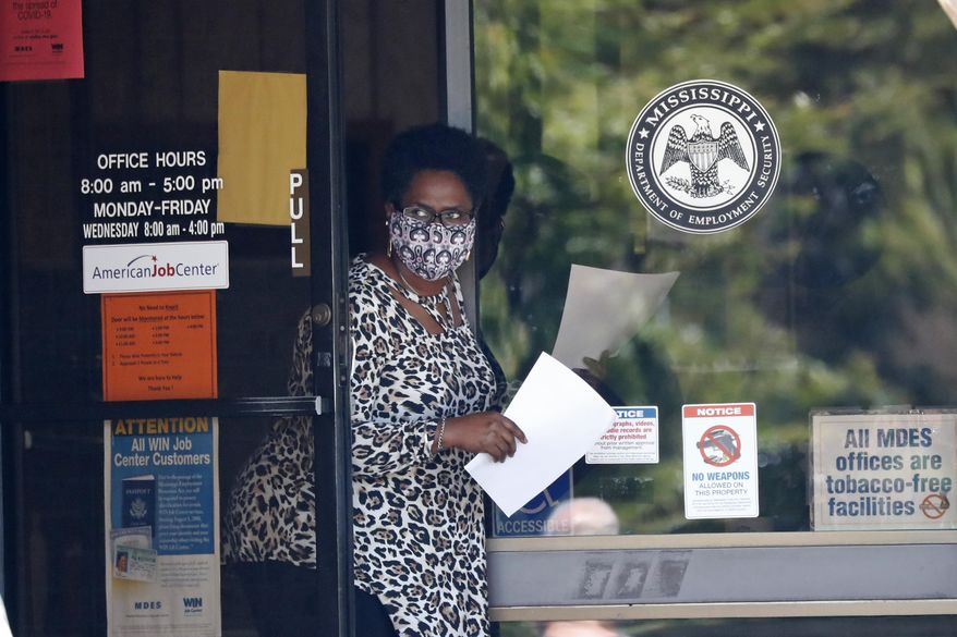 FILE - In this April 21, 2020 file photo, a worker wearing a mask to protect against coronavirus, holds an unemployment benefit application form as she waits for a client at the state WIN job center in Pearl, Miss. Friday, Dec. 4, monthly U.S. jobs report will help answer a key question hanging over the economy: Just how much damage is being caused by the resurgent coronavirus, the resulting restrictions on businesses and the reluctance of consumers to shop, travel and dine out? (AP Photo/Rogelio V. Solis, File)