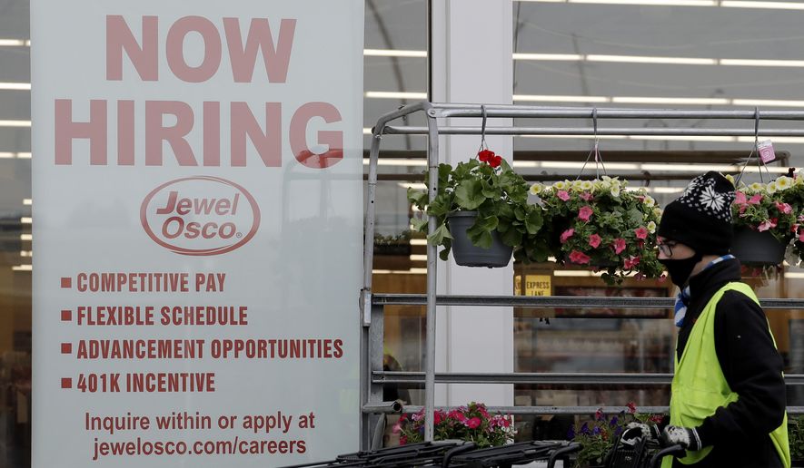 A man pushes carts as a hiring sign shows at a Jewel Osco grocery store in Deerfield, Ill., Thursday, April 23, 2020. On Friday, Dec. 4, monthly U.S. jobs report will help answer a key question hanging over the economy: Just how much damage is being caused by the resurgent coronavirus, the resulting restrictions on businesses and the reluctance of consumers to shop, travel and dine out? (AP Photo/Nam Y. Huh)