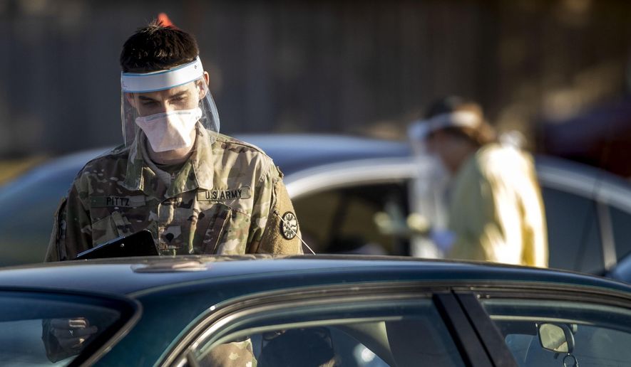 Spc. Anthony Pittz with the Idaho Army National Guard collects information from patients waiting to be tested for COVID-19 in the parking lot of Saint Alphonsus Health Plaza in Meridian, Idaho Thursday, Dec. 3, 2020. (Darin Oswald/Idaho Statesman via AP)
