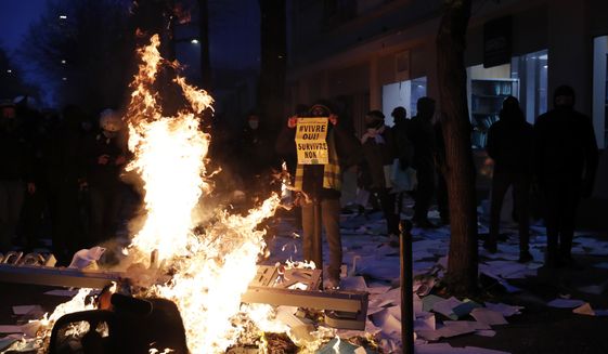 A man holds a poster reading &amp;quot;Living yes, surviving no&amp;quot; during a demonstration Saturday, Dec. 5, 2020 in Paris. Thousands marched in protests around France on Saturday against a contested security bill with tensions quickly rising at the Paris march as intruders set at least one car afire, broke windows and tossed projectiles at police. Saturday&#x27;s marches drew a diverse lot of protesters, but was focused on a security bill that includes an article aimed at banning the publication of images of police officers with intent to cause them harm. (AP Photo/Francois Mori)
