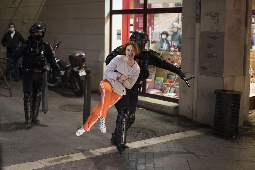 A police officer restrains a woman as police detain her friend during a demonstration against a security law that would restrict sharing images of police, Saturday, Nov. 28, 2020, in Marseille, France. Civil liberties groups and journalists are concerned that the measure will stymie press freedoms and allow police brutality to go undiscovered and unpunished. The cause has gained fresh impetus in recent days after footage emerged of French police officers beating up a Black man, triggering a nationwide outcry. (AP Photo/Daniel Cole)