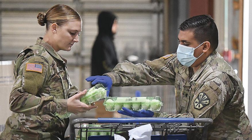 U.S. Army Arizona National Guard Spc. Jordyn VanWormer, left, and Spc. Angel Lopez load eggs into a shopping cart inside Yuma Community Food Bank, early Friday morning, Dec. 4, 2020, in Yuma, Ariz. It was the Guard's last day working at the Food Bank. Soldiers had been assisting with serving the needs of Yumans since April during the COVID-19 pandemic. (Randy Hoeft/The Yuma Sun via AP) **FILE**