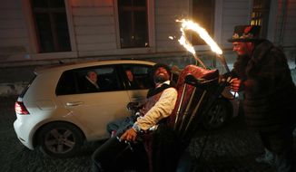 Members of the new circus company Cirk La Putyka entertain people driving through with their cars in Prague, Czech Republic, Saturday, Dec. 5, 2020. On the eve of St. Nicholas, Czechs traditionally celebrate by dressing up as Devils, Angels and St. Nicholas, and visiting children in their homes handing out small presents, coal, potatoes or other gifts. Due to  government’s restrictive measures usual traditions would be impossible. A new circus company in Prague offered a solution Saturday. They invited the kids to drive with parents their in cars through the heaven and hell they created, with devils jumping in a distance and angels flying above them.  The eager visitors formed a long line of cars at the La Putyka Circus base in Prague. (AP Photo/Petr David Josek)