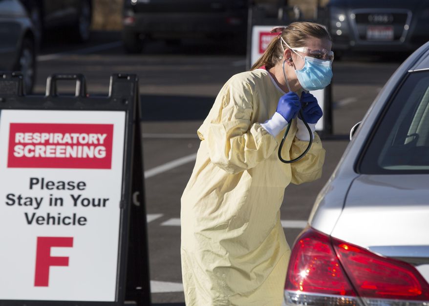 Physician assistant Nicole Thomas conducts a COVID-19 examination in the parking lot at Primary Health Medical Group&#39;s clinic in Boise, Idaho, Tuesday, Nov. 24, 2020. The urgent-care clinic revamped into a facility for coronavirus patients as infections and deaths surge in Idaho and nationwide. Some 1,000 people have died due to COVID-19, and infections this week surpassed 100,000. (AP Photo/Otto Kitsinger)
