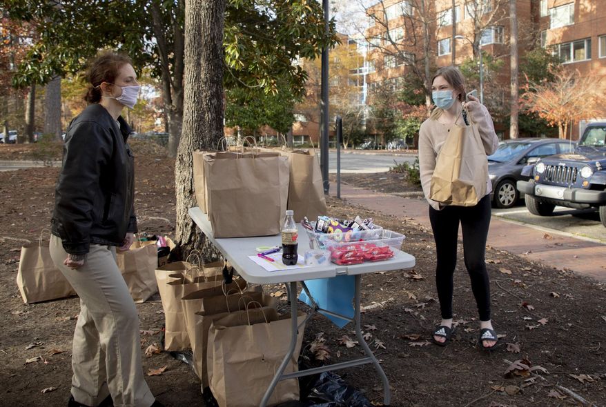 Jenny Deview, right, picks up meals from Jamie Sohn, a member of The Chapel Hill &amp;amp; Carrboro Mothers Club, which is providing free meals to UNC-Chapel Hill students staying on campus over the seven weeks of their extended and isolated winter break during the COVID-19 pandemic, on Wednesday, Dec. 2, 2020, in Chapel Hill, N.C. (Casey Toth/The News &amp;amp; Observer via AP)