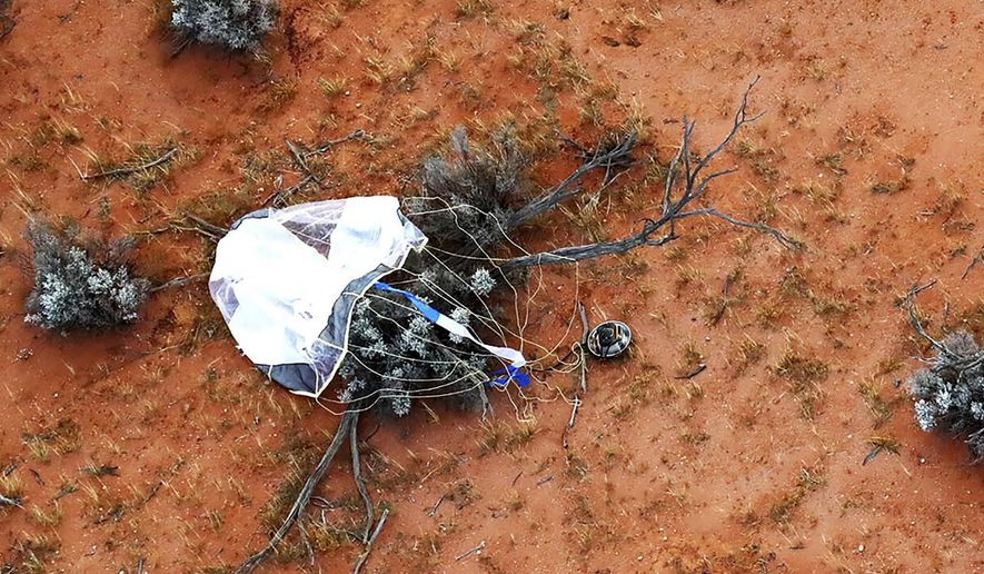 In this photo provided by the Japan Aerospace Exploration Agency (JAXA), a capsule, center, dropped by Hayabusa2 is seen before being retrieved in Woomera, southern Australia, Sunday, Dec. 6, 2020. A Japanese capsule carrying the first samples of asteroid subsurface shot across the night atmosphere early Sunday before successfully landing in the remote Australian Outback, completing a mission to provide clues to the origin of the solar system and life on Earth. (JAXA via AP)
