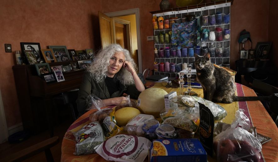 Phyllis Marder poses with her cat, Nellie, with food she recently obtained from a local food bank in the dining room of her home in Evanston, Ill., on Thursday, Nov. 5, 2020. At first, Marder, 66, didn’t tell anyone about going to food pantries. Then she had a change of heart. “Keeping a secret makes things get worse,” she says ’”… and makes me feel worse about myself, and so I decided that it was more important to talk about it.&amp;quot; (AP Photo/Charles Rex Arbogast)