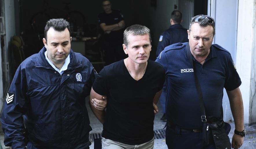 FILE - In this Oct.4, 2017 file photo, police officers escort Alexander Vinnik, center as they leave a courthouse at the northern Greek city of Thessaloniki. The Russian bitcoin expert at the center of a multi-country legal tussle was sentenced in Paris on Monday to five years in prison for money laundering and ordered to pay 100,000 in fines in a case of suspected cryptocurrency fraud. (AP Photo/Giannis Papanikos, File)