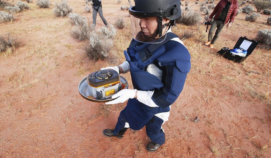 FILE - In this Sunday, Dec. 6, 2020 photo provided by the Japan Aerospace Exploration Agency (JAXA), a member of JAXA retrieves a capsule dropped by Hayabusa2 in Woomera, southern Australia. The small capsule from Japan’s Hayabusa2 spacecraft successfully landed in a sparsely populated desert in the Australian Outback on Sunday. (JAXA via AP, File)