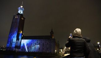 Stockholm City Hall is lit up with art inspired by the discovery of black holes, during the Nobel Week Lights  in Stockholm, Sweden, Saturday Dec. 5, 2020.  The Nobel Week is opening with a visual projections light display in Stockholm. (Jessica Gow / TT via AP)