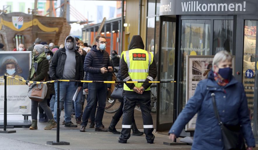 People line up in front of a shop after the stores reopen after a lock down in Vienna, Austria, Monday Dec. 7, 2020., 2020. The Austrian government has moved to restrict freedom of movement for people, in an effort to slow the onset of the COVID-19 coronavirus. (AP Photo/Ronald Zak)