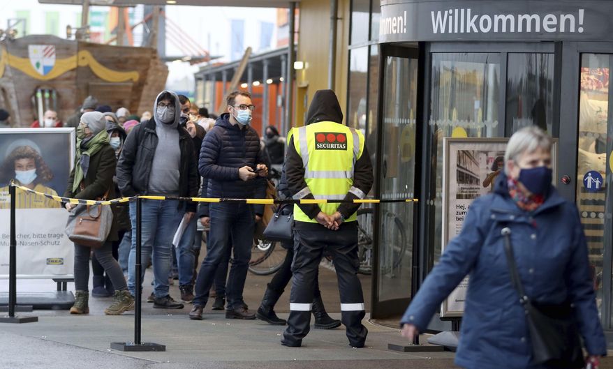 People line up in front of a shop after the stores reopen after a lock down in Vienna, Austria, Monday Dec. 7, 2020., 2020. The Austrian government has moved to restrict freedom of movement for people, in an effort to slow the onset of the COVID-19 coronavirus. (AP Photo/Ronald Zak)
