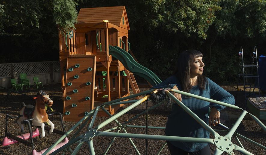 Mary De La Rosa stands inside a play structure in her home backyard, that once housed the now-closed child care program, Creative Explorers, Wednesday, Oct. 21, 2020, in Los Angeles. When De La Rosa closed her toddler and preschool program in March because of the coronavirus pandemic, she fully expected to serve the children again some day. In the end, though, Creative Explorers closed for good. The story of De La Rosa’s program is being repeated across the country as the pandemic’s effects ripple through child care, disproportionately affecting Black and Latino-owned centers in an industry that has long relied on providers of color. (AP Photo/Damian Dovarganes)