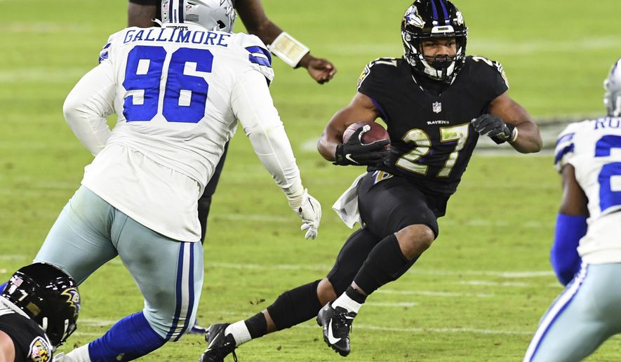 Baltimore Ravens running back J.K. Dobbins (27) runs the ball against Dallas Cowboys defensive tackle Neville Gallimore (96) during the second half of an NFL football game, Tuesday, Dec. 8, 2020, in Baltimore. (AP Photo/Terrance Williams)