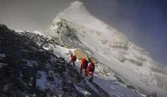 FILE - In this May 27, 2020, file photo released by Xinhua News Agency, members of a Chinese surveying team head for the summit of Mount Everest, also known locally as Mt. Qomolangma. China and Nepal have jointly announced on Tuesday, Dec. 8, 2020, a new height for Mount Everest, ending a discrepancy between the two nations. (Tashi Tsering/Xinhua via AP, File)