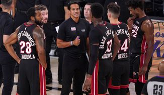 FILE - In this Sept. 23, 2020, file photo, Miami Heat coach Erik Spoelstra, center, talks to the team during a timeout in the second half of Game 4 of the NBA basketball Eastern Conference final against the Boston Celtics in Lake Buena Vista, Fla. For NBA coaches, masks are required this season. Jackets are not. Rules for coaching attire will be relaxed by the league this year, though not as much as was the case during play at the bubble at Walt Disney World this past summer. Suit jackets or sport coats will not be required — but coaches won’t be able to wear the short-sleeved shirts that most donned for games in the bubble, either. (AP Photo/Mark J. Terrill, File)