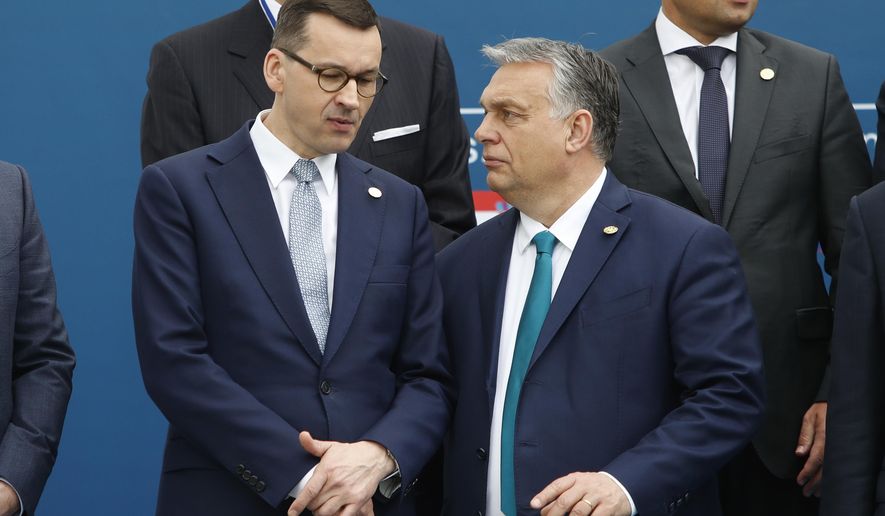FILE - In this Feb. 1, 2020 file photo, Poland&#39;s Prime Minister Mateusz Morawiecki, left, and Hungary&#39;s Prime Minister Victor Orban share a word as they line up for a group picture prior to a meeting in Beja, Portugal. Polish government officials insisted on Friday, Dec. 4, 2020, that they are sticking to their tough negotiating position ahead of a key European Union summit next week that should finalize the bloc’s next seven-year budget and a major pandemic recovery package. (AP Photo/Armando Franca, File)