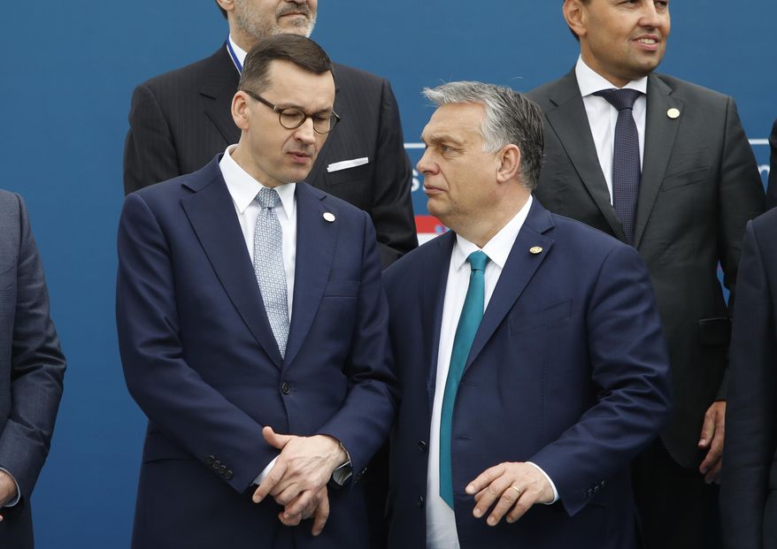 FILE - In this Feb. 1, 2020 file photo, Poland&#39;s Prime Minister Mateusz Morawiecki, left, and Hungary&#39;s Prime Minister Victor Orban share a word as they line up for a group picture prior to a meeting in Beja, Portugal. Polish government officials insisted on Friday, Dec. 4, 2020, that they are sticking to their tough negotiating position ahead of a key European Union summit next week that should finalize the bloc’s next seven-year budget and a major pandemic recovery package. (AP Photo/Armando Franca, File)
