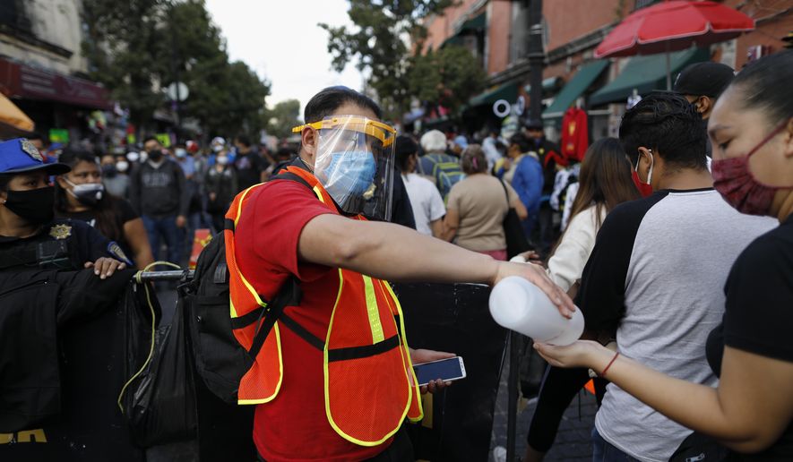 A city worker offers antibacterial gel to passing shoppers as they walk in a crowded commercial district of central Mexico City, Saturday, Dec. 5, 2020. With hospitals once again filling up with COVID-19 patients, Mexico City&#39;s mayor on Friday urged people to stay at home as much as possible and authorized checkpoints to limit the number of people entering the capital&#39;s colonial-era downtown at one time. (AP Photo/Rebecca Blackwell)